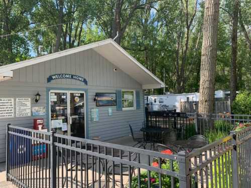 A cozy building with a "Welcome Home" sign, surrounded by trees and outdoor seating.