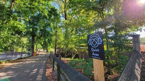 A path through a lush green area with a sign that reads "Quiet Area" surrounded by trees.