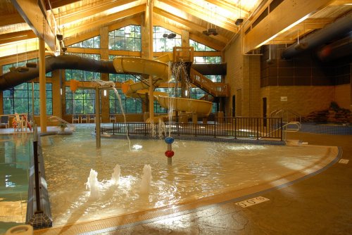 Indoor water park featuring slides, a splash area, and large windows for natural light.