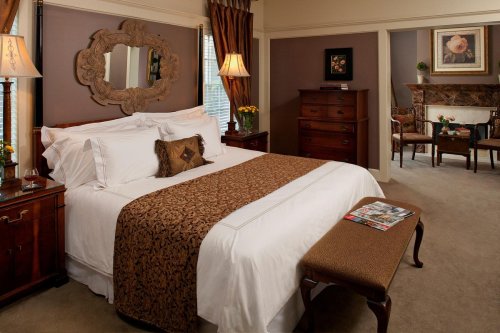 Cozy bedroom with a large bed, decorative mirror, and elegant furnishings, featuring warm colors and soft lighting.