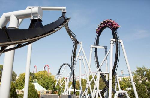 A roller coaster with a steep loop and track, with riders enjoying the thrill against a clear blue sky.