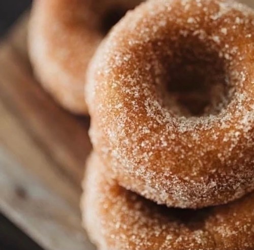 A close-up of freshly baked, sugar-coated donuts on a wooden surface.