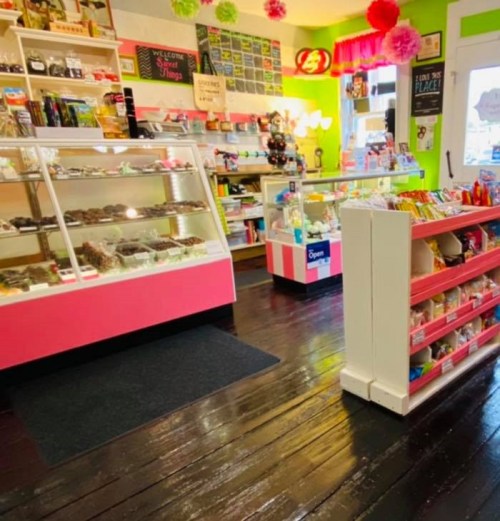 Brightly colored candy shop interior with display cases and shelves filled with sweets and snacks.