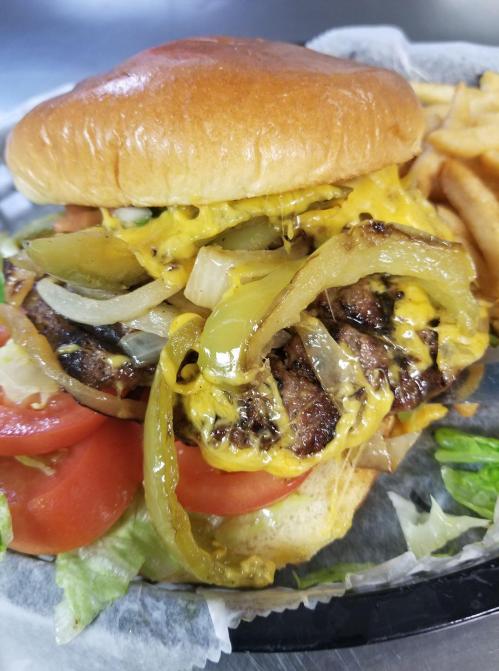 A juicy cheeseburger with melted cheese, grilled onions, lettuce, and tomatoes, served with a side of fries.