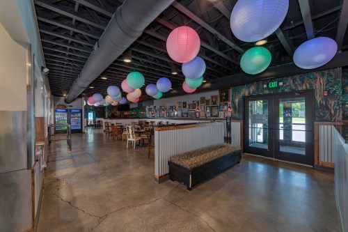 Interior of a restaurant featuring colorful lanterns, a seating area, and a welcoming entrance.