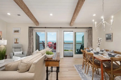 Cozy living area with a view of the ocean, featuring a dining table, sofa, and sliding glass doors to a deck.