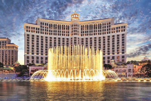 The Bellagio Hotel with its iconic fountain display, illuminated against a twilight sky.