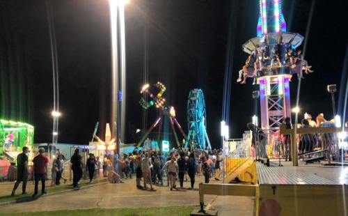A lively night scene at a carnival with colorful lights, rides, and a crowd enjoying the festivities.