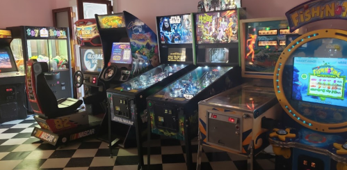 A colorful arcade room featuring various games, including pinball machines and racing simulators.