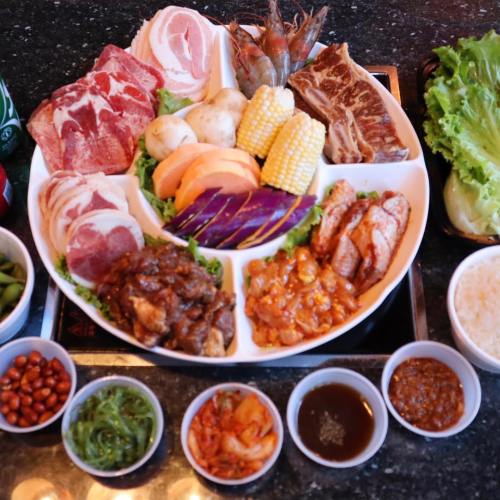 A platter of assorted meats, seafood, and vegetables, accompanied by small bowls of sauces and side dishes.