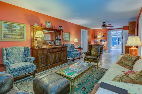 Cozy living room with colorful walls, vintage furniture, and a mix of seating, featuring a coffee table and decorative items.