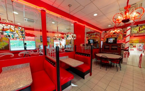 Brightly lit diner interior with red booths, stained glass lamps, and a retro vibe.
