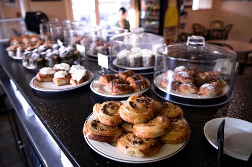 A display of various pastries and desserts in a café, including cinnamon rolls and chocolate croissants.