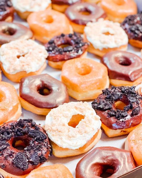 A variety of colorful donuts, including chocolate, glazed, and cream-filled, arranged in a box.