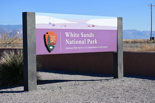 Sign for White Sands National Park, featuring the National Park Service logo and desert landscape in the background.