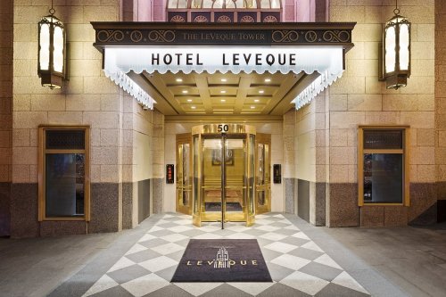 Entrance of Hotel LeVeque, featuring a revolving door and elegant signage, with a patterned floor mat.