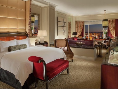 Luxurious hotel room featuring a king bed, elegant furnishings, and a stunning city view at dusk.