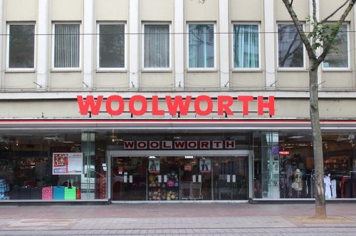 Facade of a Woolworth store with large red signage and glass entrance, surrounded by a city street.