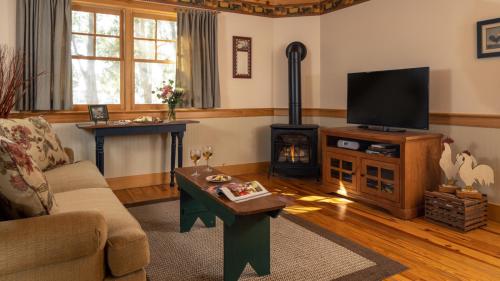 Cozy living room with a sofa, wooden furniture, a TV, and a stove, featuring warm lighting and decorative accents.