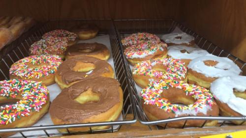 A display of assorted donuts, including chocolate and white frosted varieties topped with colorful sprinkles.