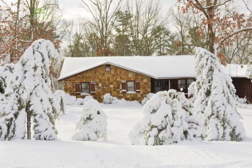 A cozy stone house surrounded by snow-covered trees in a winter landscape.