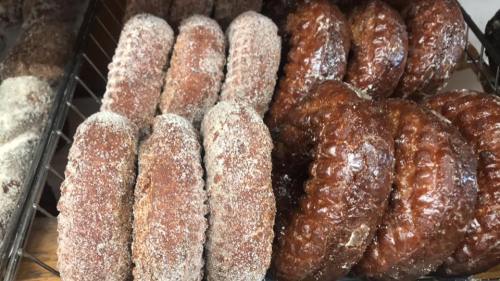 A close-up of assorted donuts, including sugar-coated and glazed varieties, arranged in a display.