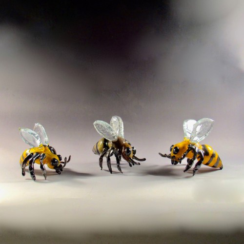 Three decorative bees with yellow and black stripes, transparent wings, and detailed features, arranged in a row.