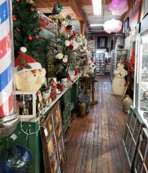 A festive shop aisle filled with holiday decorations, vintage items, and a snowman figure, all on wooden floors.