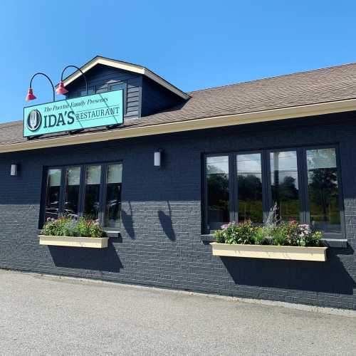 Exterior of Ida's Restaurant, featuring a sign and flower boxes under large windows on a sunny day.