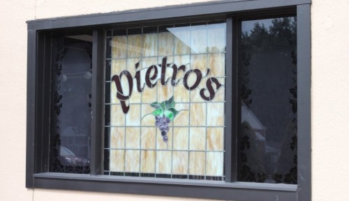 Stained glass window with the name "Pietro's" and grapevine design.