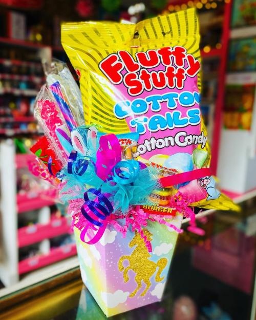 Colorful gift basket featuring cotton candy, candy sticks, and decorative ribbons in a unicorn-themed container.