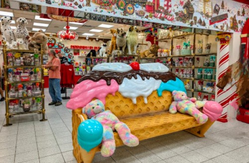 A whimsical ice cream-themed bench with plush teddy bears, surrounded by colorful toys and decorations in a playful store.