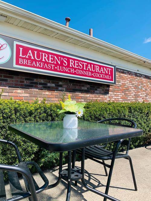 A table with a small plant sits outside Lauren's Restaurant, which offers breakfast, lunch, dinner, and cocktails.