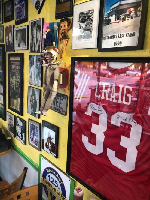 A wall decorated with framed photos, memorabilia, and a red football jersey featuring the name "Craig" and the number 33.
