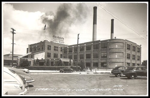 Historic black-and-white photo of Gerber's Baby Foods factory in Piedmont, Michigan, with smoke rising from chimneys.
