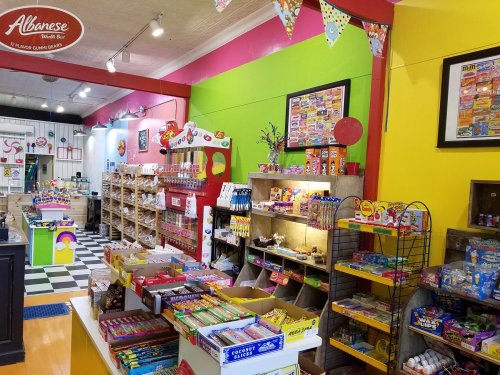 Colorful candy store interior with shelves of sweets, snacks, and vibrant wall decor.
