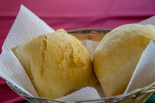 A close-up of two golden, flaky pastries in a woven basket lined with paper towels.