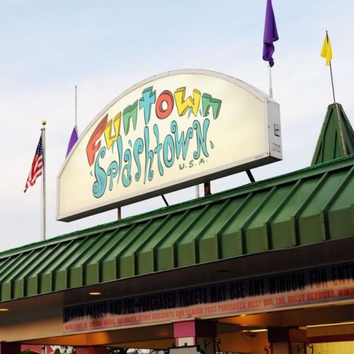 Sign for Funtown Splashtown U.S.A. with colorful lettering and flags, set against a green roof.
