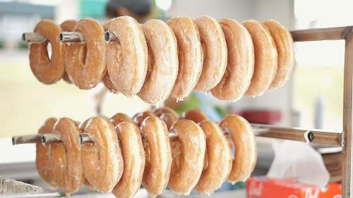 A display of glazed donuts hanging on a rack, showcasing their shiny, golden-brown surface.