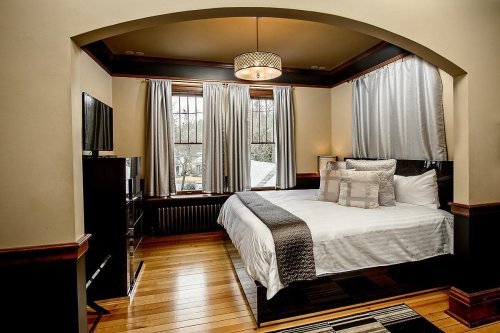 Cozy bedroom featuring a queen bed, large windows, elegant curtains, and modern decor.