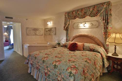 Cozy bedroom with floral bedding, a large bed, and a jacuzzi tub, featuring soft lighting and elegant decor.