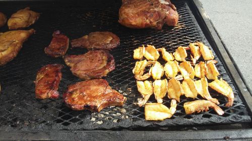 Grilled meats and shrimp on a barbecue grill, showcasing a variety of cooked dishes.