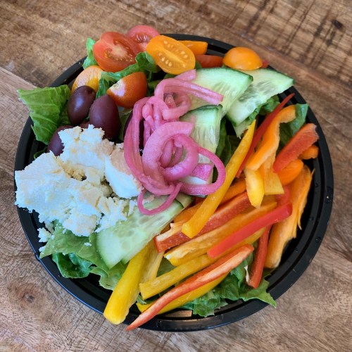 A colorful salad with lettuce, cucumbers, tomatoes, bell peppers, olives, pickled onions, and a sprinkle of cheese.