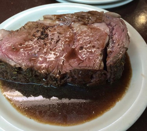 A slice of juicy roast beef on a plate, glistening with gravy.
