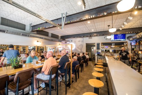 A bustling restaurant interior with patrons seated at a long bar, enjoying meals and drinks in a cozy atmosphere.