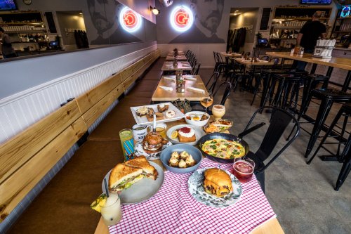 A vibrant restaurant table filled with various dishes, including sandwiches, desserts, and drinks, in a stylish setting.