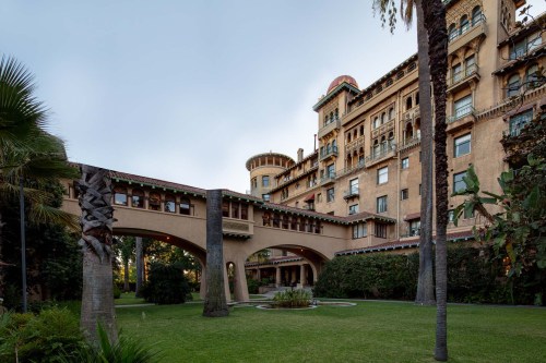 A historic building with unique architecture, featuring arches and lush greenery in the foreground.