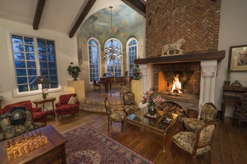 Cozy living room with a fireplace, elegant furniture, and a scenic view through large windows.