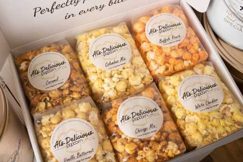 A box of assorted popcorn flavors, including caramel, cheddar, and white chocolate, neatly packaged in clear bags.