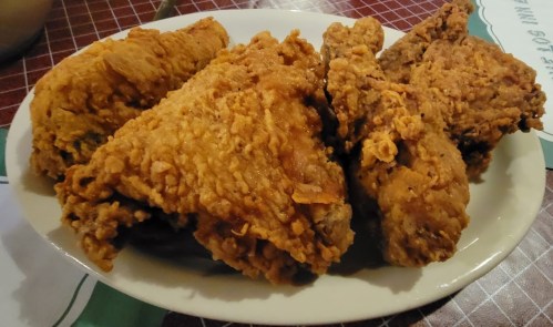 A plate of crispy fried chicken pieces arranged neatly, showcasing a golden-brown, crunchy texture.